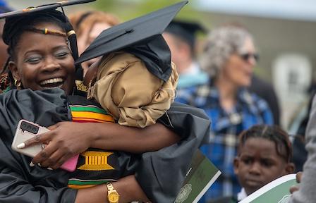 Recent graduate at commencement hugging their supporter